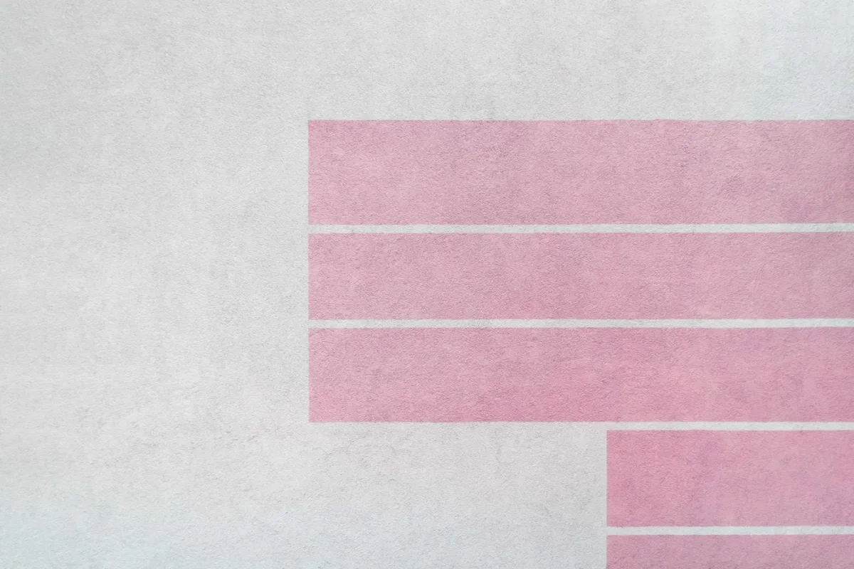 Pink bars on a plaster wall, read as a rising chart — the monthly report